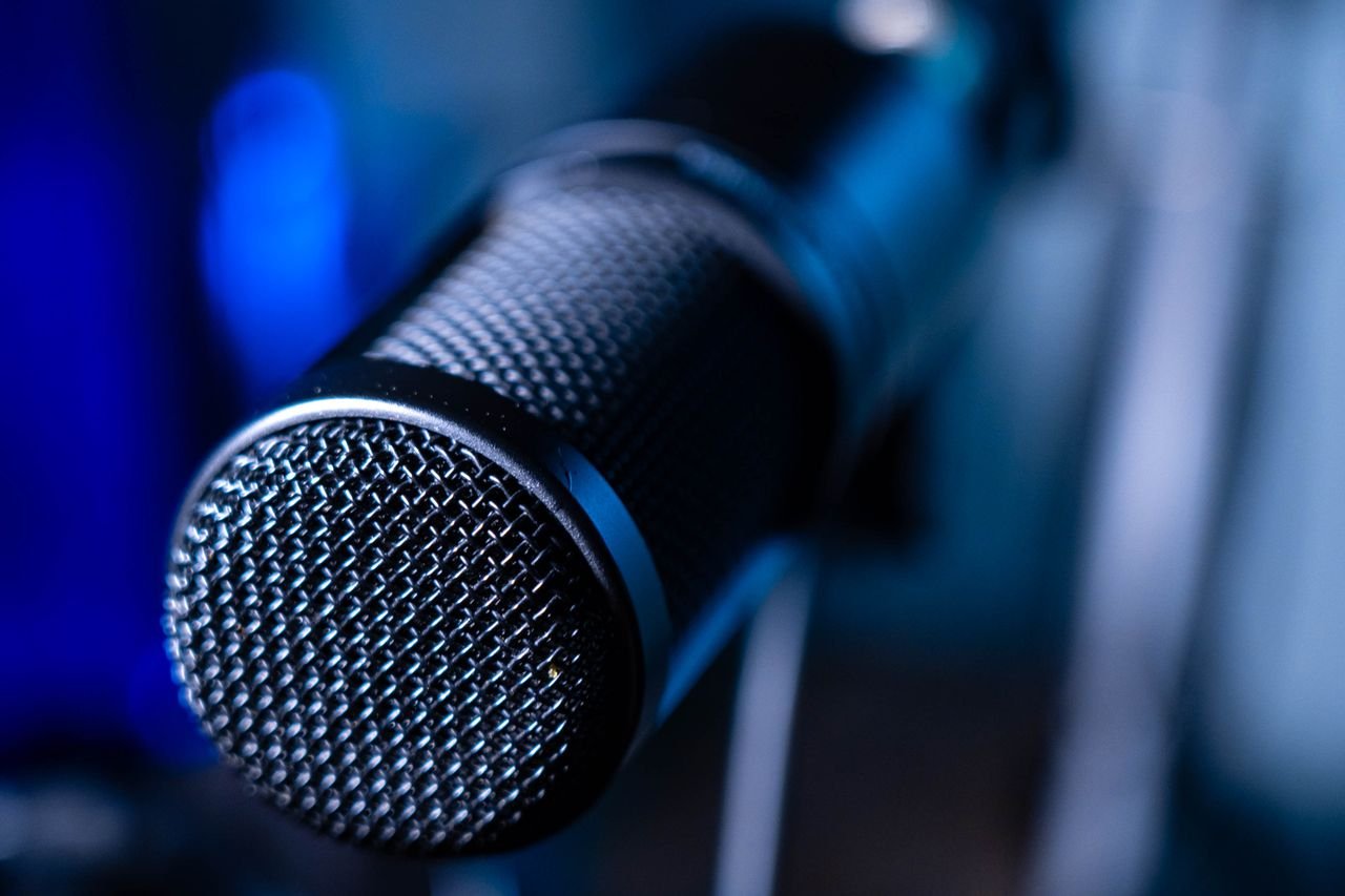 About Detailed close-up of a professional studio microphone with a blurred blue background.