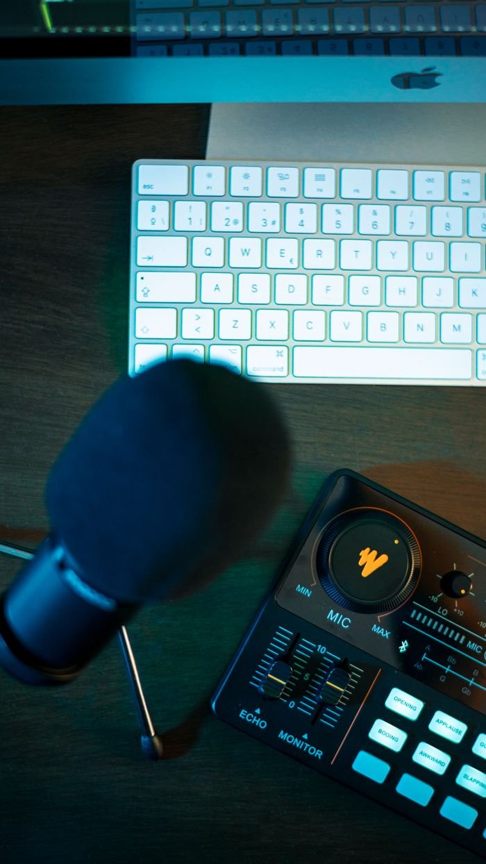 About A sleek podcasting setup featuring a microphone, audio control panel, and keyboard.
