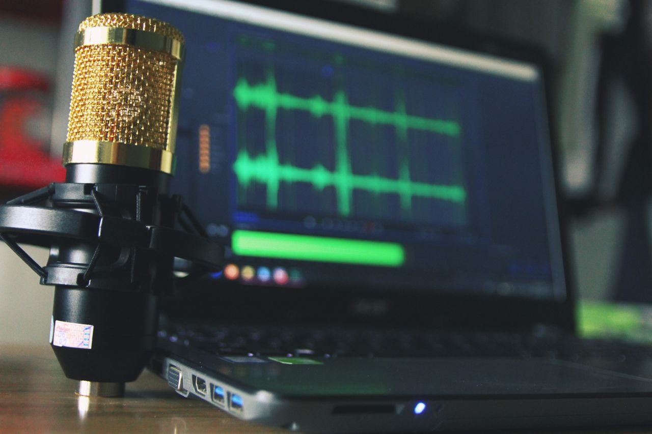 Services Close-up of a golden microphone and laptop used for audio editing.