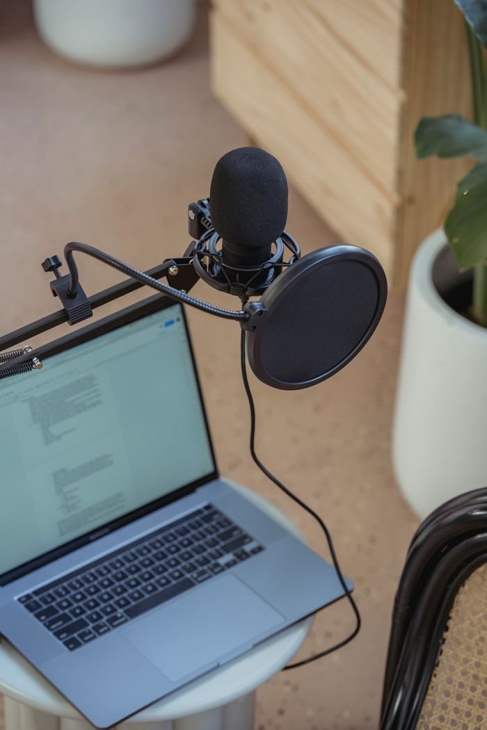 The Art of Drawing Readers In: Your attractive post title goes here From above of modern opened laptop with microphone on tripod placed on small table near chair during recording radio program